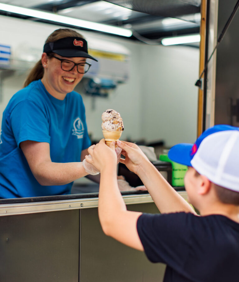 Mait handing an ice cream cone to a boy